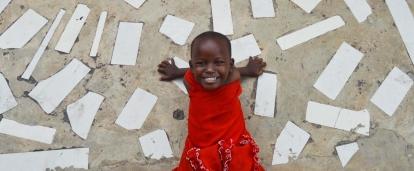 During a Projects Abroad Care placement a child poses outside a care centre in Tanzania. In an project volunteering with children in Tanzania a child smiles outside a care centre.